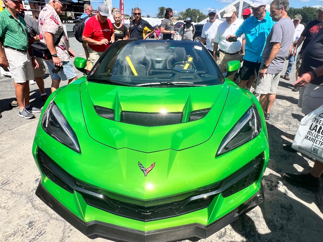 Bright green Corvette C8 parked at Corvettes at Carlisle event, surrounded by enthusiastic fans and car lovers.