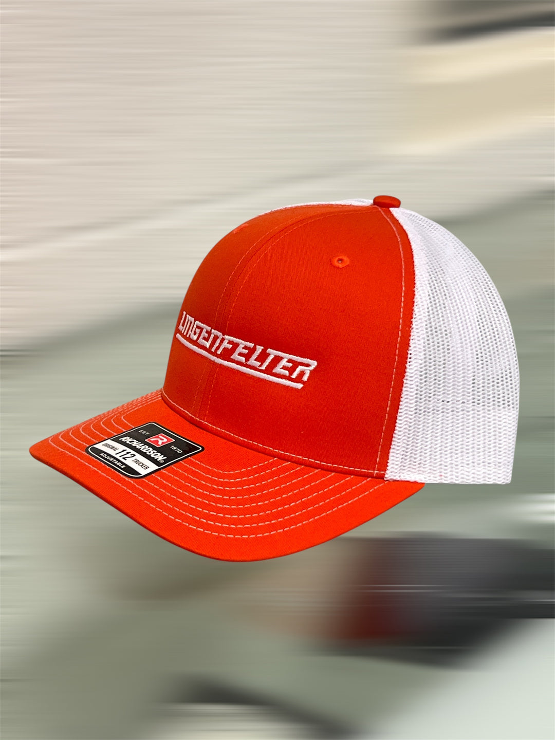 Orange and white cap with a brand logo on a blurred background