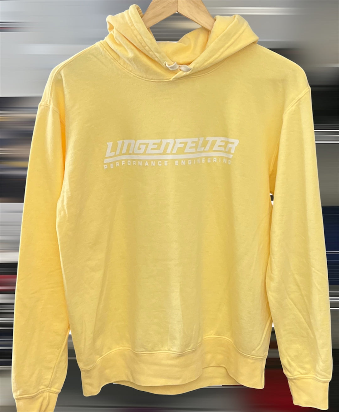 Yellow hoodie with 'Lingenfelter' branding on a hanger against a metallic background