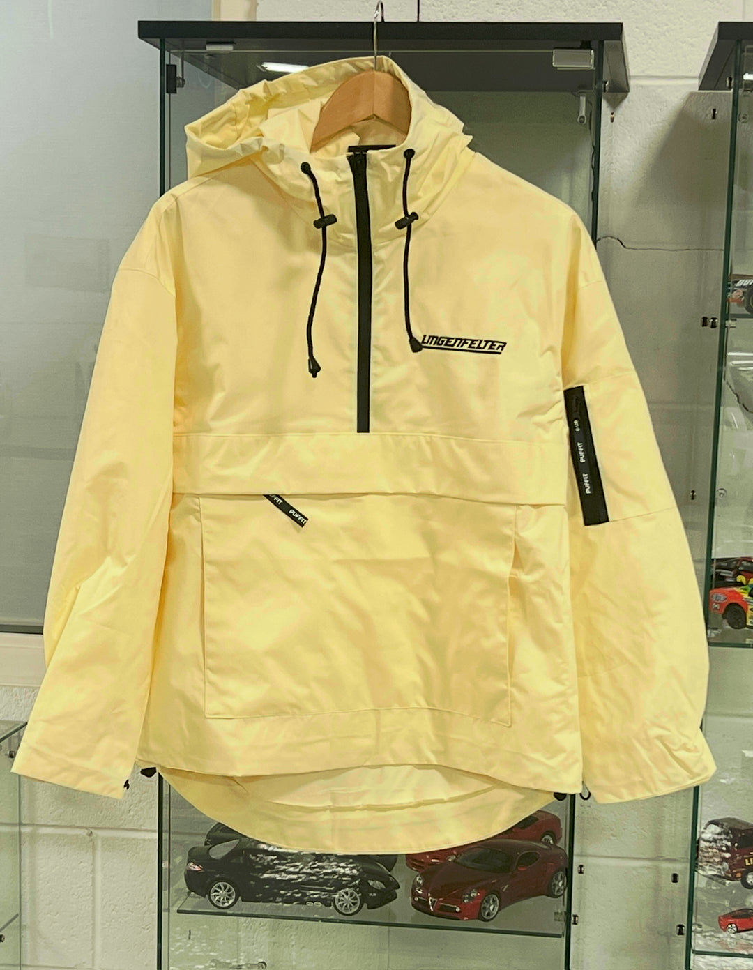Beige jacket with a brand logo on a glass display case.